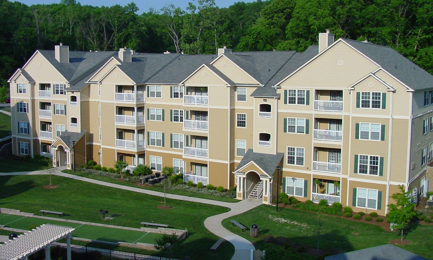 Large apartment complex with beige and brown vinyl siding, white trim, and multiple balconies.