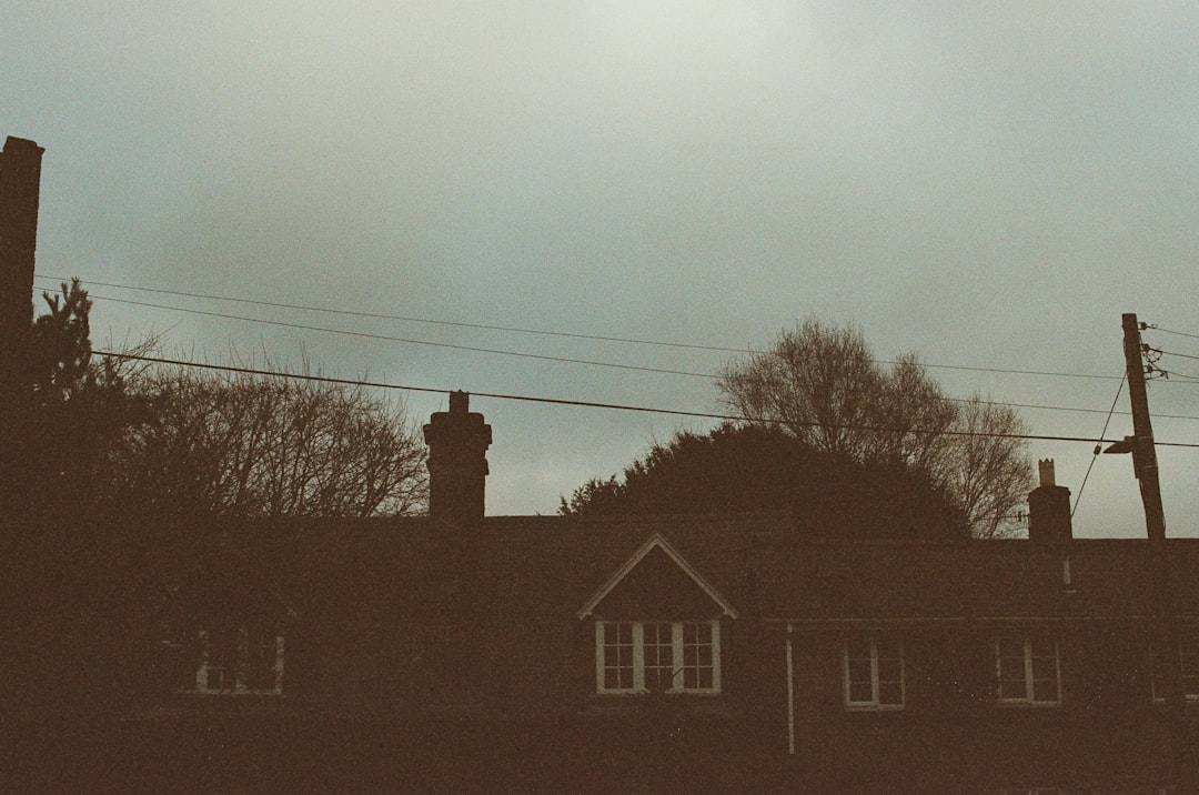 Dramatic, dark storm clouds gathering over a residential home in a Louisiana-style neighborhood, symbolizing the threat of...